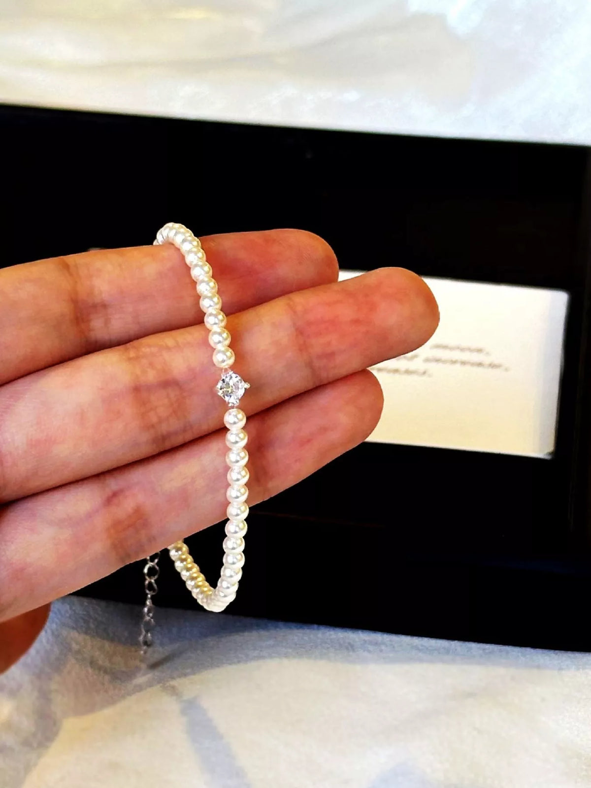 Adjustable pearl bracelet held between fingers to show the strand and clasp.
