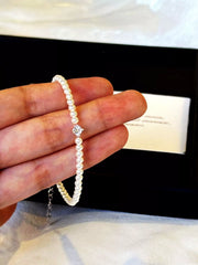Adjustable pearl bracelet held between fingers to show the strand and clasp.