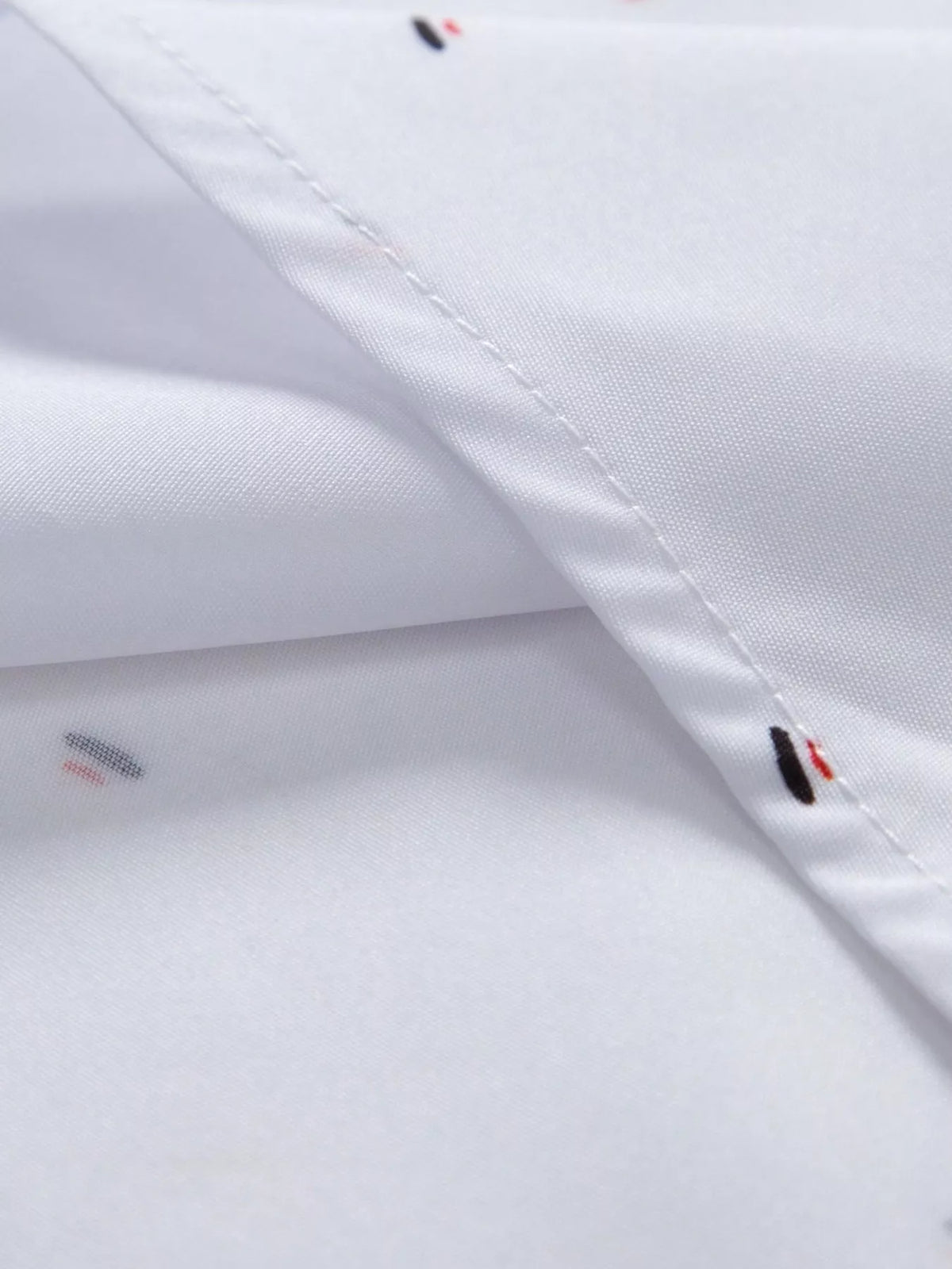 Close-up of neatly stitched shirt seam beside the tiny red and black print