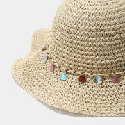 Close-up of the multicolour disc trim on the beige straw-woven hat