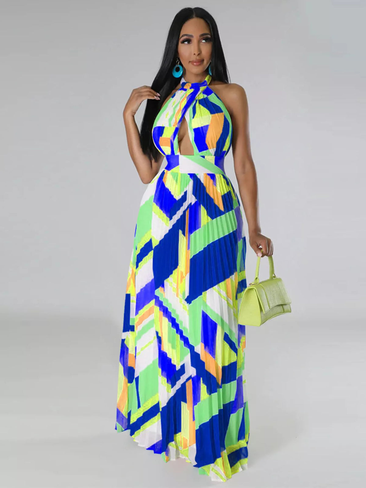 Front view of a blue and lime geometric halter dress on a model carrying a light green handbag.