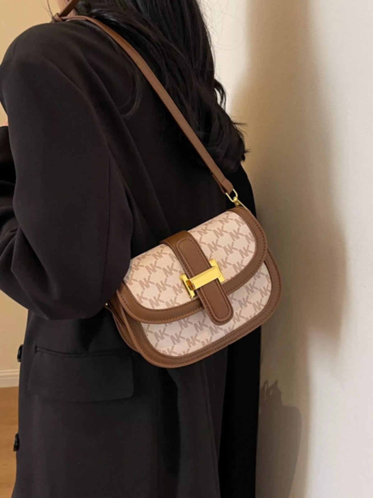 Cream patterned flap bag with brown edging and a gold-coloured clasp, worn at the hip