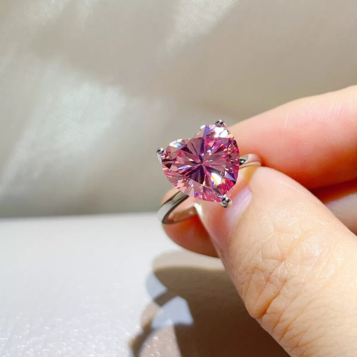 Angled close-up showing the pink heart stone and prongs.