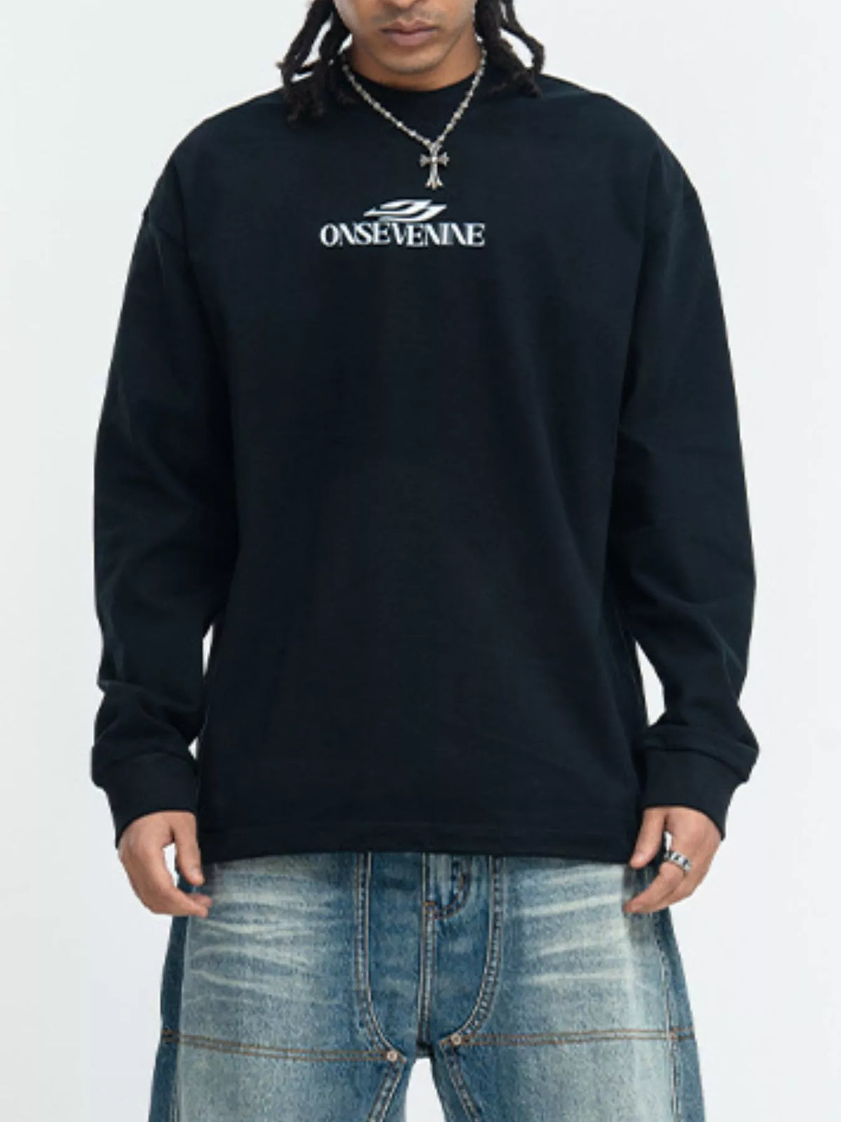 Model wearing a black long-sleeve shirt with small white chest lettering