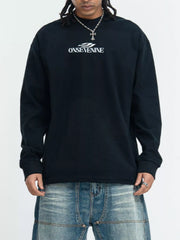 Model wearing a black long-sleeve shirt with small white chest lettering