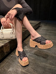 Black woven cross-strap platform sandals worn while seated on steps