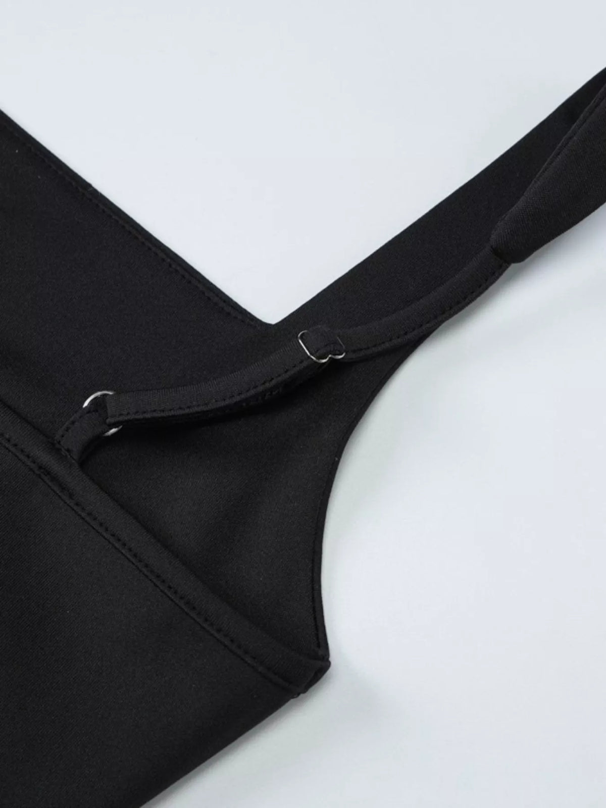 Close-up of the black dress's side slit and ruched fabric.