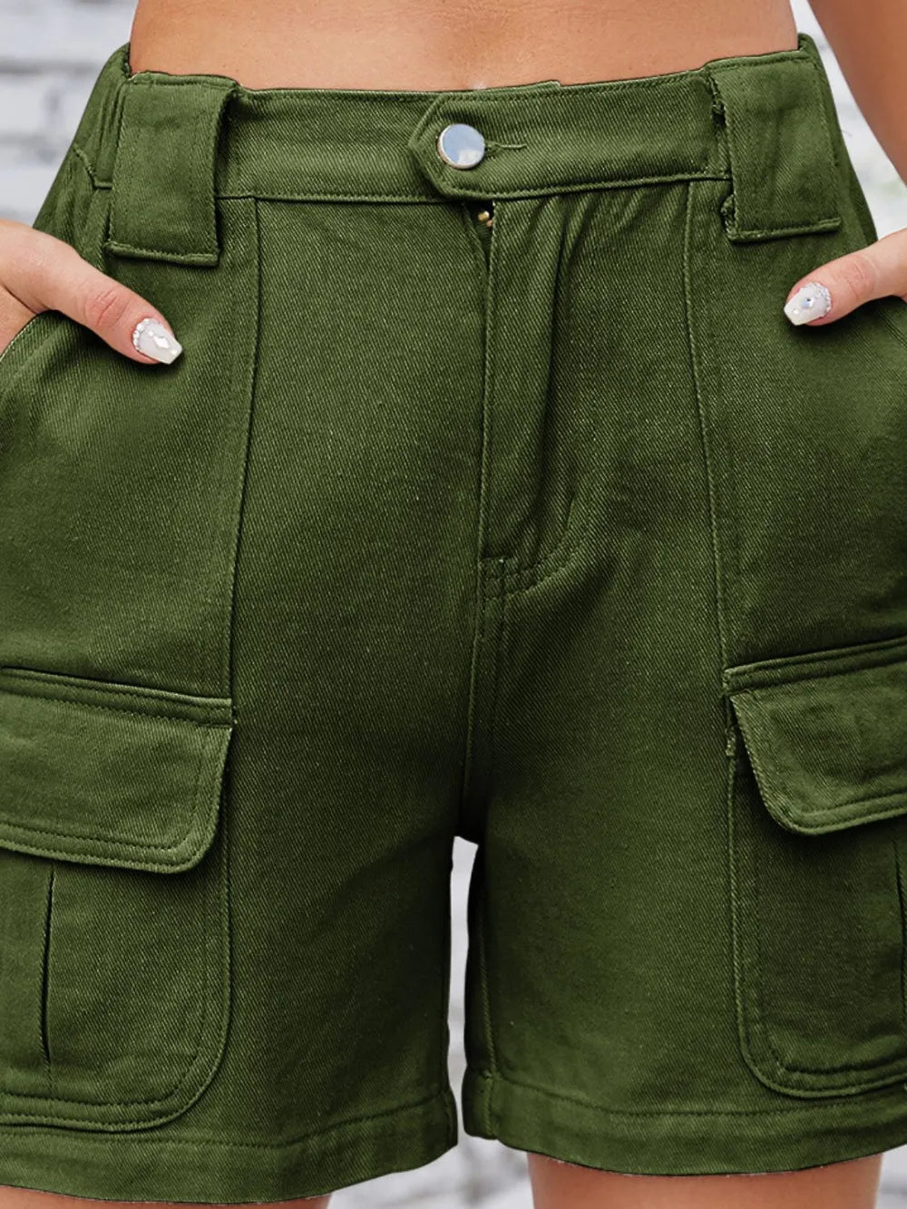 Close-up of olive cargo shorts showing button waist and pocket flap.