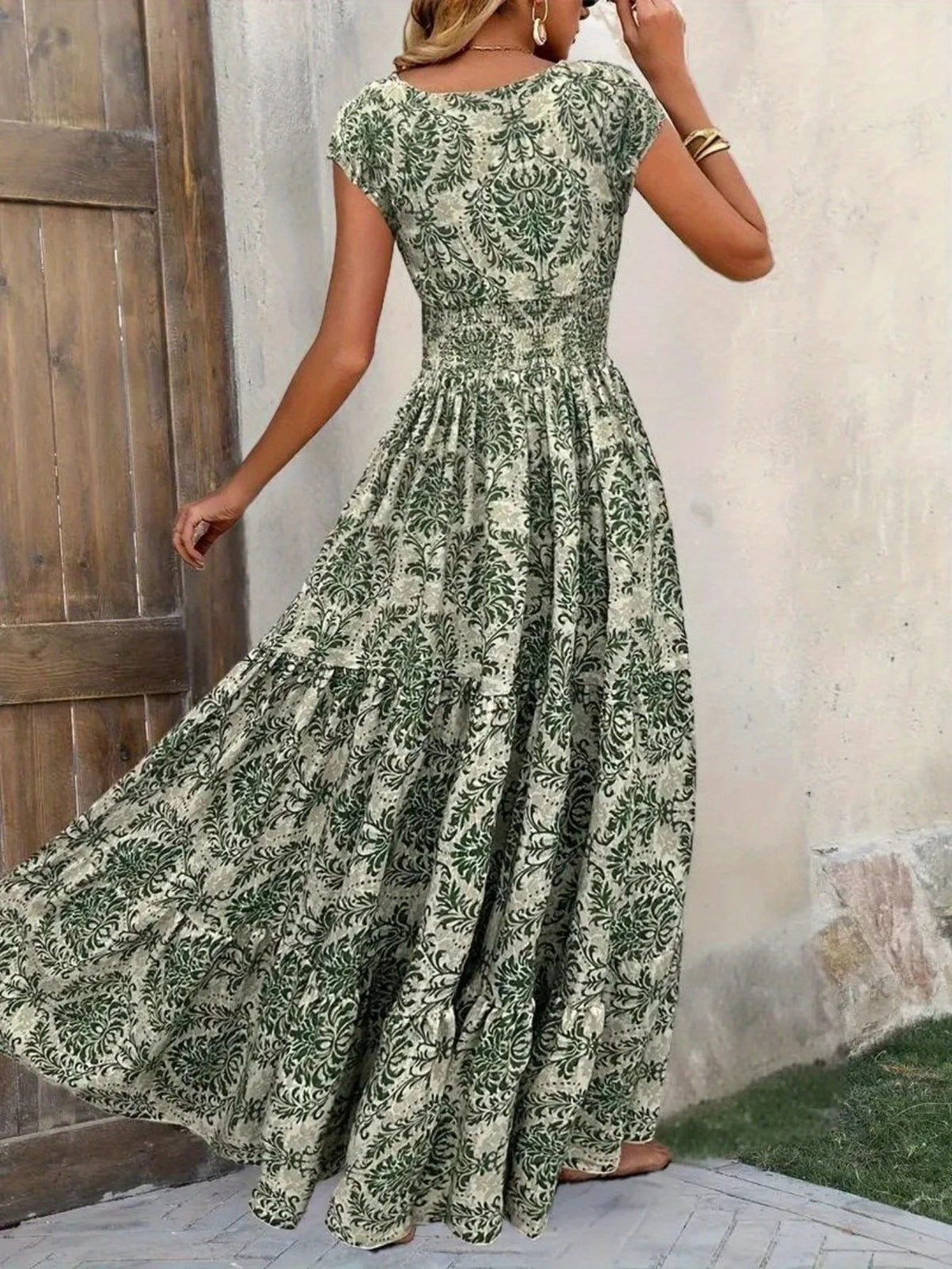 Blue-gray floral cap-sleeve maxi dress with smocked bodice, shown full length with skirt gathered at one side.