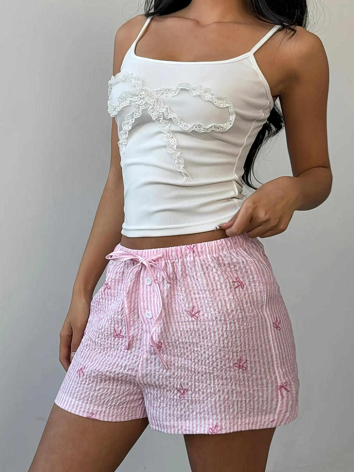 Model wearing pink plaid bow-detail shorts, front view