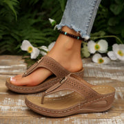 Taupe toe-post wedge sandals with perforated straps shown on feet