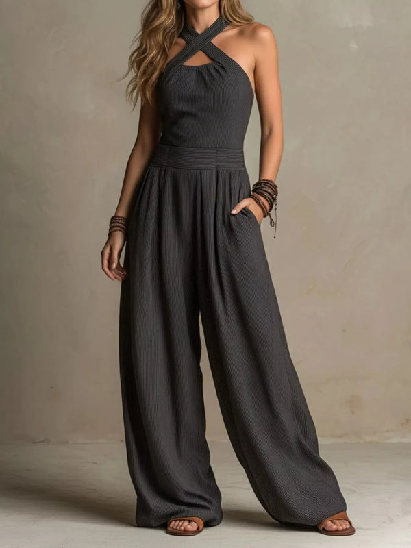 Charcoal halter jumpsuit shown from the front with one hand in a pocket.