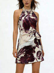 Front view of a cream and deep burgundy abstract-print halter mini dress with a waist tie.