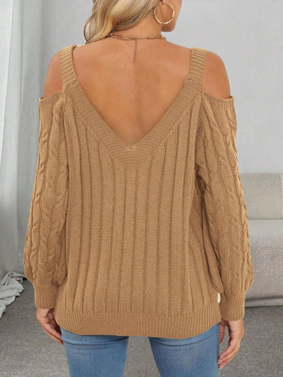 Back view of tan cable-knit sweater with V neckline and open shoulders