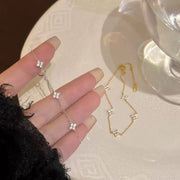 Silver bracelet and clover charms displayed across a hand