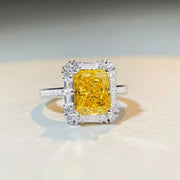 Front view of rectangular yellow gemstone ring with a clear-stone frame