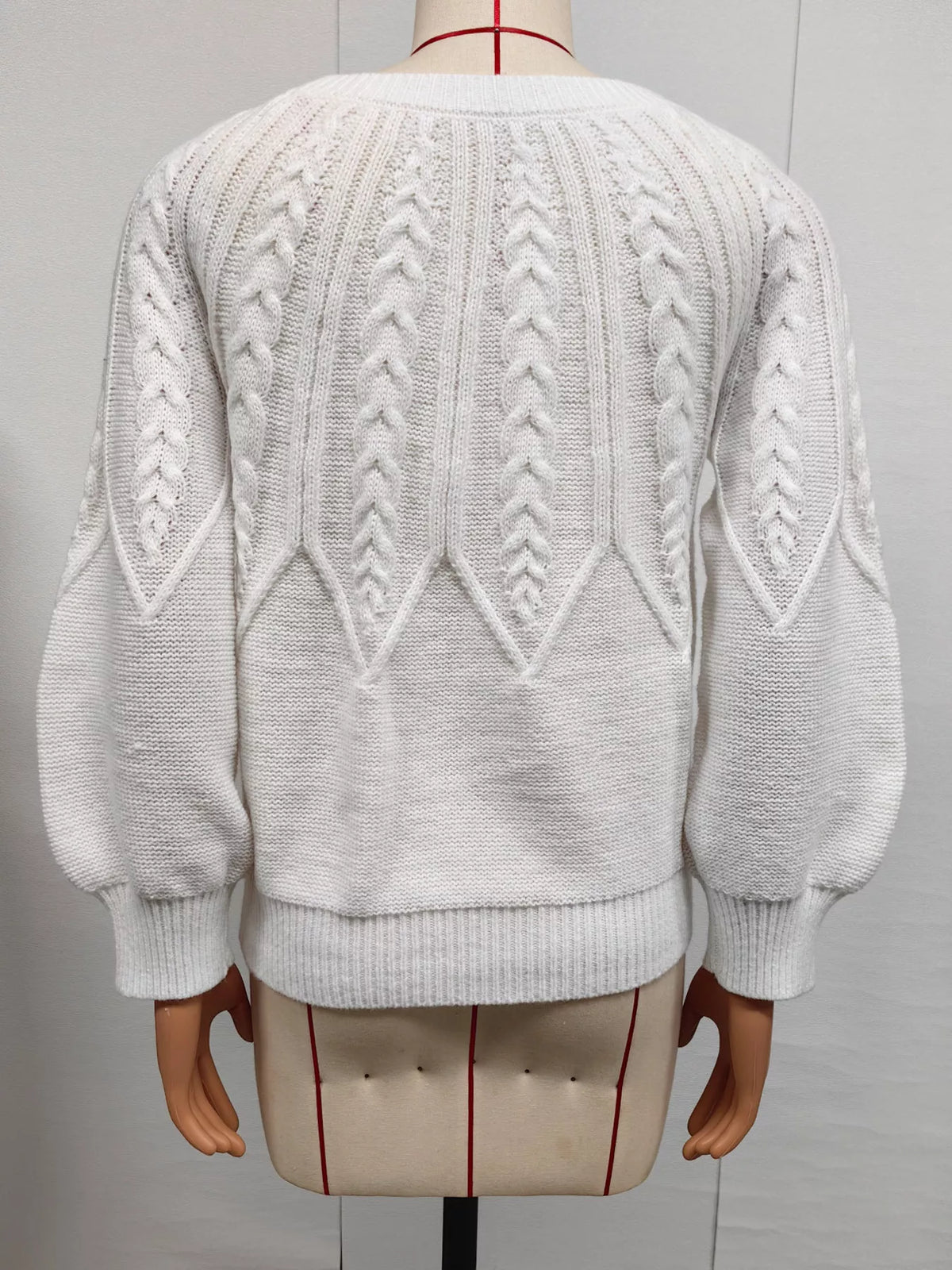 Back of white cable-knit sweater displayed on a mannequin