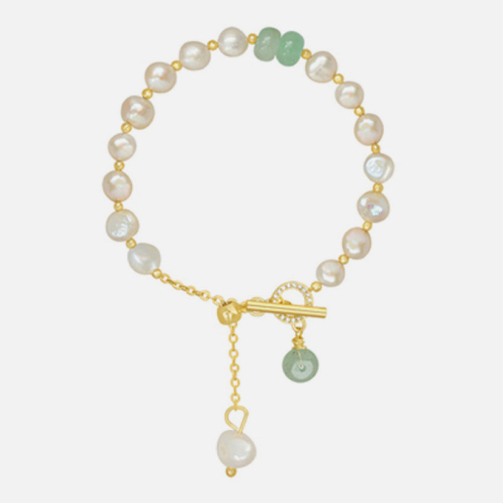 Pearl and green stone link bracelet arranged on a light background