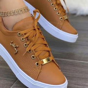 Close view of brown perforated lace-up sneaker with metal eyelets and decorative side accent