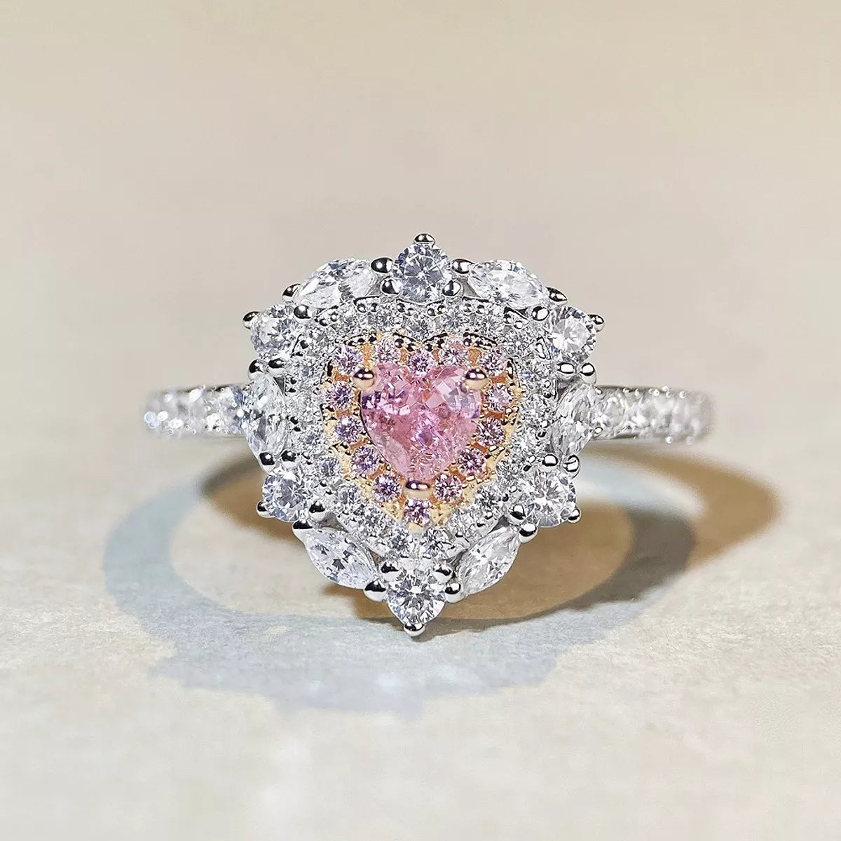 Front view of a heart-shaped pink stone surrounded by clear stones on a silver-tone ring.