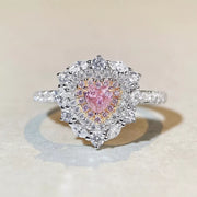 Front view of a heart-shaped pink stone surrounded by clear stones on a silver-tone ring.
