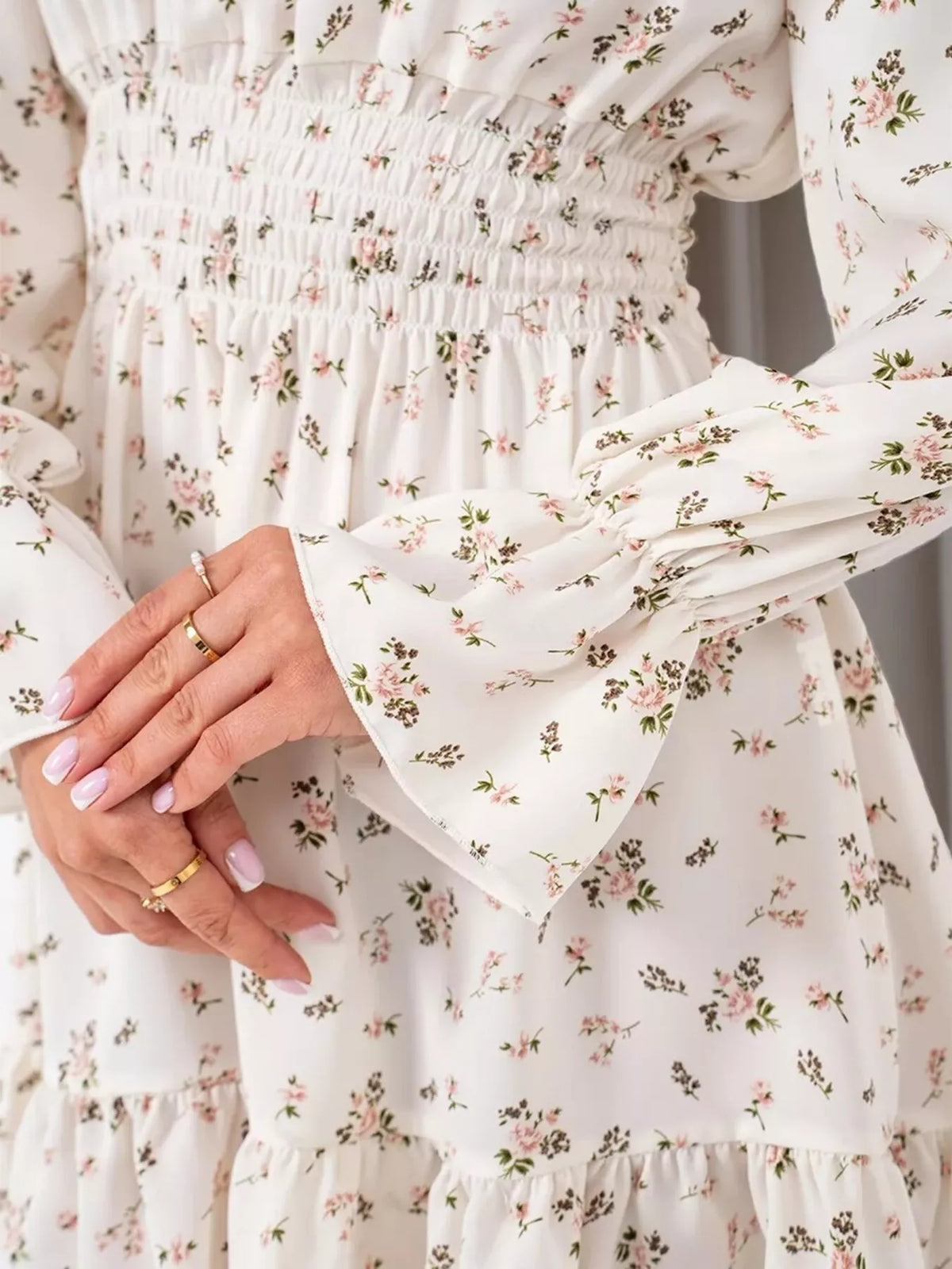 Close-up of the white floral dress's gathered smocked waist and printed fabric.