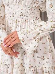 Close-up of the white floral dress's gathered smocked waist and printed fabric.