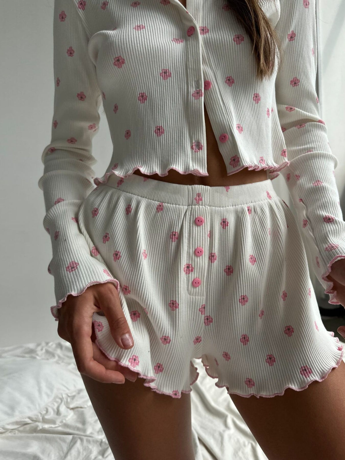 Close view of white floral-print ribbed top and pink buttons