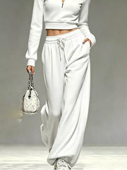 White matching pants and cropped top with drawstring waist, model carrying handbag