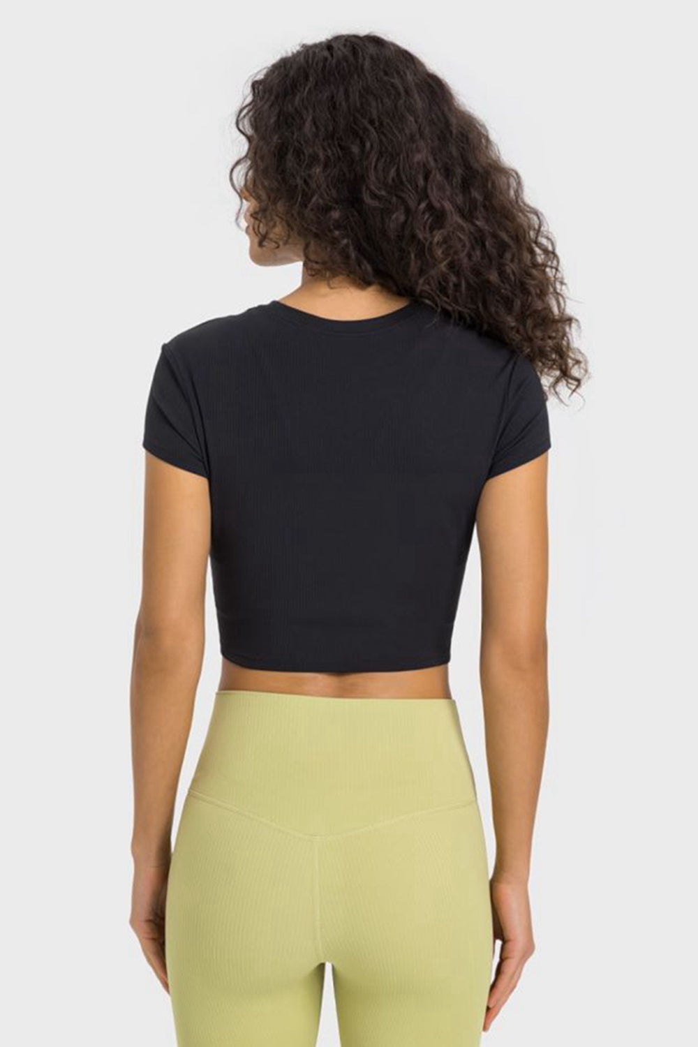 Back view of black cropped T-shirt paired with pale yellow leggings