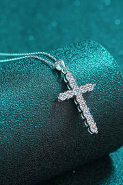Cross pendant necklace draped over a teal display cushion