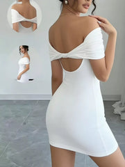Back view of the white off-shoulder mini dress, showing crossed fabric bands and an open back.