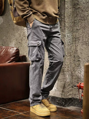 Gray cargo pants with large flap thigh pockets modeled with a brown sweatshirt.