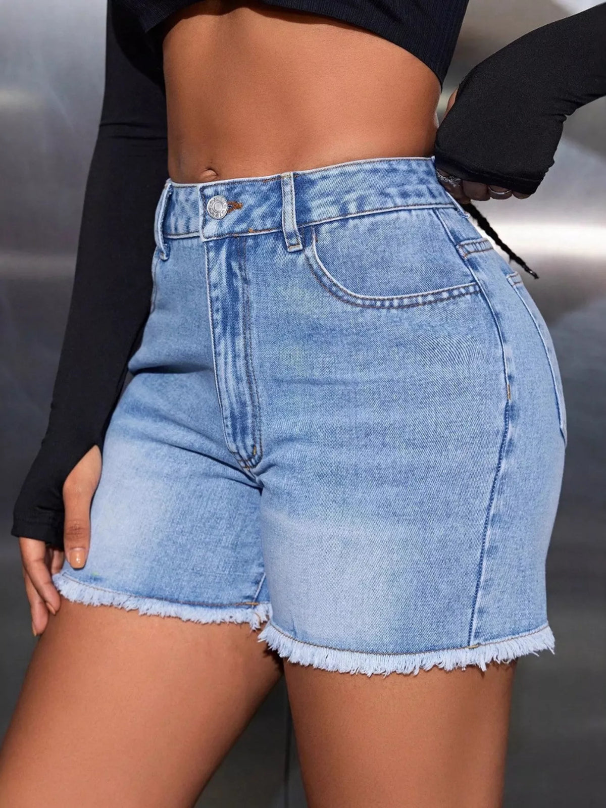 Side view of light-wash high-waisted denim shorts with frayed hems