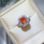 Top view of orange center stone ring with clear halo