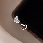 Heart studs with pavé and open heart designs against dark background