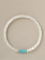Overhead view of a white beaded bracelet with a turquoise center accent