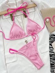 Pink ribbed bikini top and matching bottoms with hot pink straps laid flat