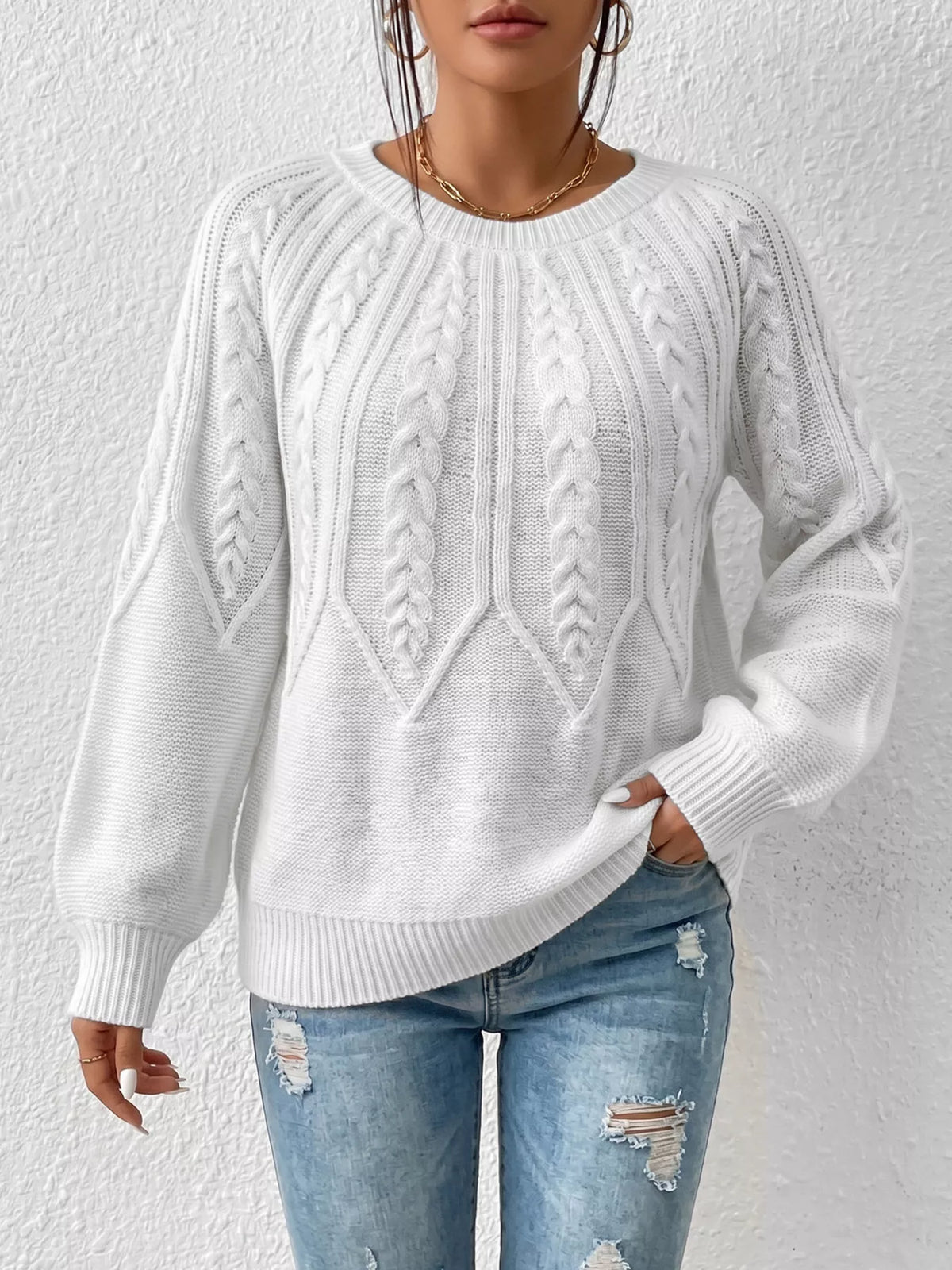 White cable-knit round-neck sweater shown from the front on a model