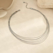 Close view of silver-tone layered necklace showing strands and clasp on cream surface