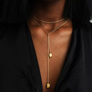 Gold-plated Y necklace with two vertical oval charms worn over a black top