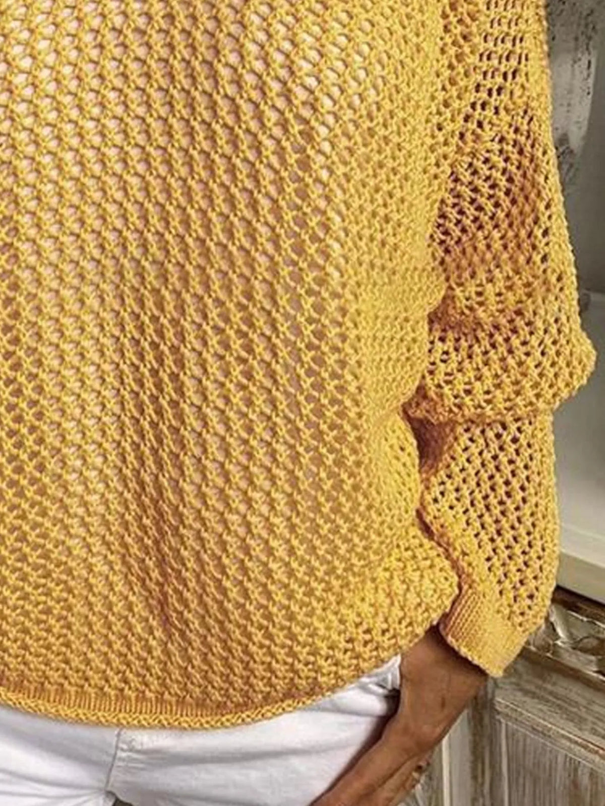 Mustard yellow knit cover-up showing the lower front, long sleeve and hem above white shorts.