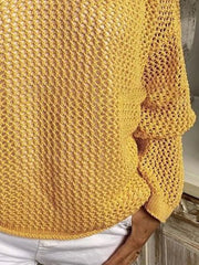 Mustard yellow knit cover-up showing the lower front, long sleeve and hem above white shorts.