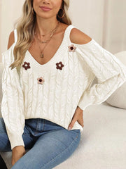 White floral-appliqué sweater shown in a seated pose, sleeves draped at sides