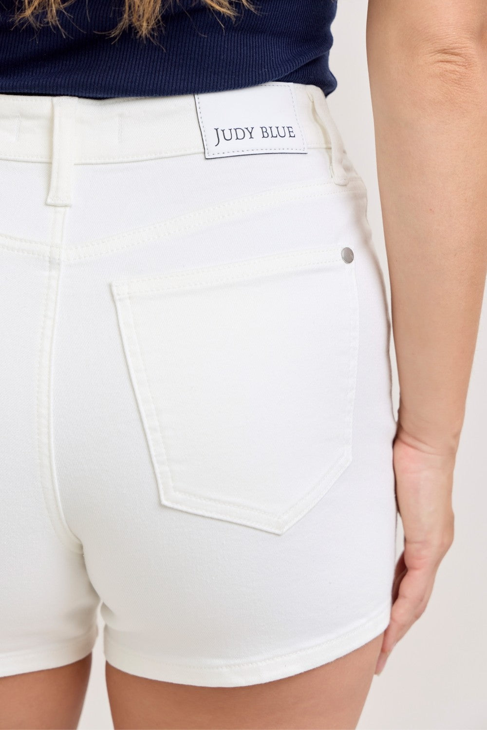 Close-up of the rear pocket and waistband label on white denim shorts.