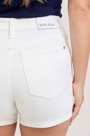 Close-up of the rear pocket and waistband label on white denim shorts.