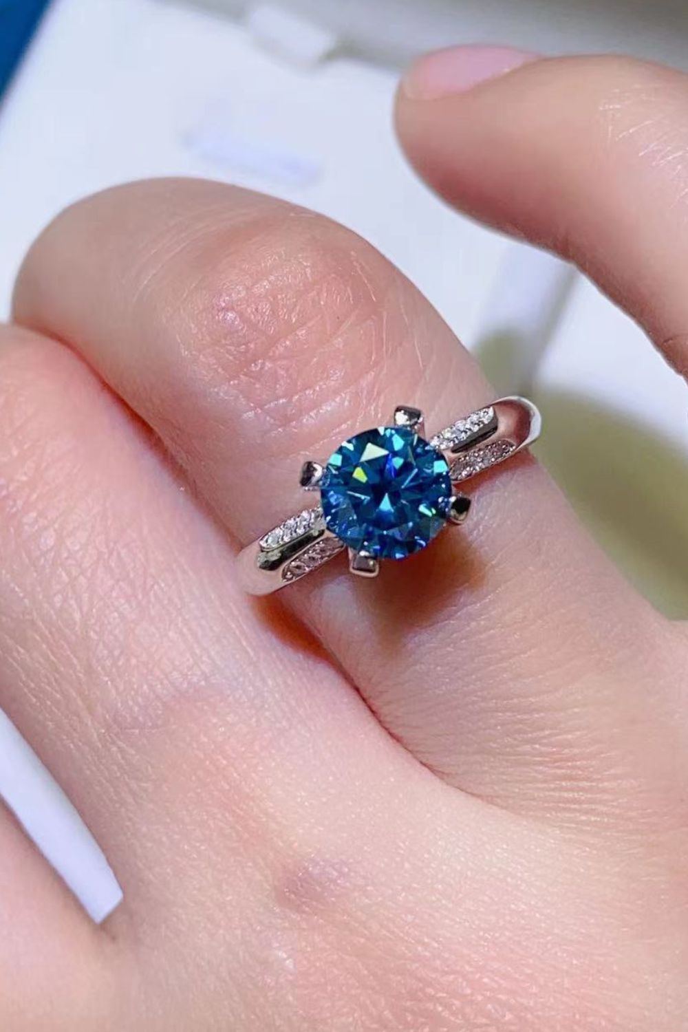 Sky-blue moissanite solitaire ring worn on a finger