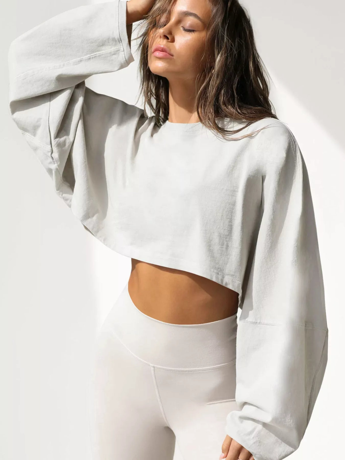 Model wearing a light gray cropped sweatshirt, front view