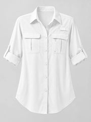 White button-down shirt laid flat with chest pocket, zip pocket and rolled sleeve details