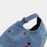 Close view of adjustable strap and cherry embroidery on denim cap